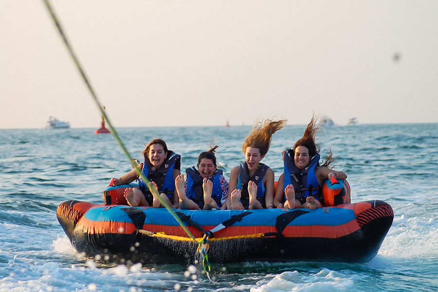 Friends enjoying boat activities in Palm Jumeirah including donut rides, jet skiing and banana boat adventures on Dubai waters